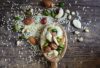 mixed nuts and seeds on wooden spoon over table including pine nuts almonds pistachios and cashews